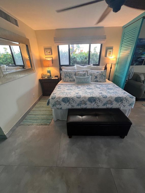 King bed under a ceiling fan beside louvered windows in the beachfront condo with pool on St. Thomas