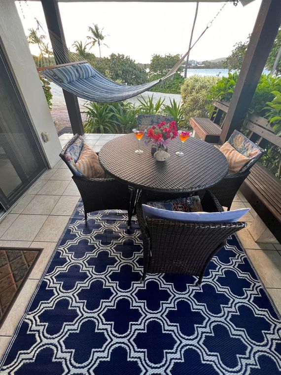Patio with a hammock and dining table a few steps from the sand at this St. Thomas rental with early check-in on request