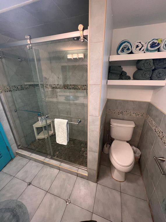 Stone-tiled walk-in shower with a low threshold in the St. Thomas condo with no stairs